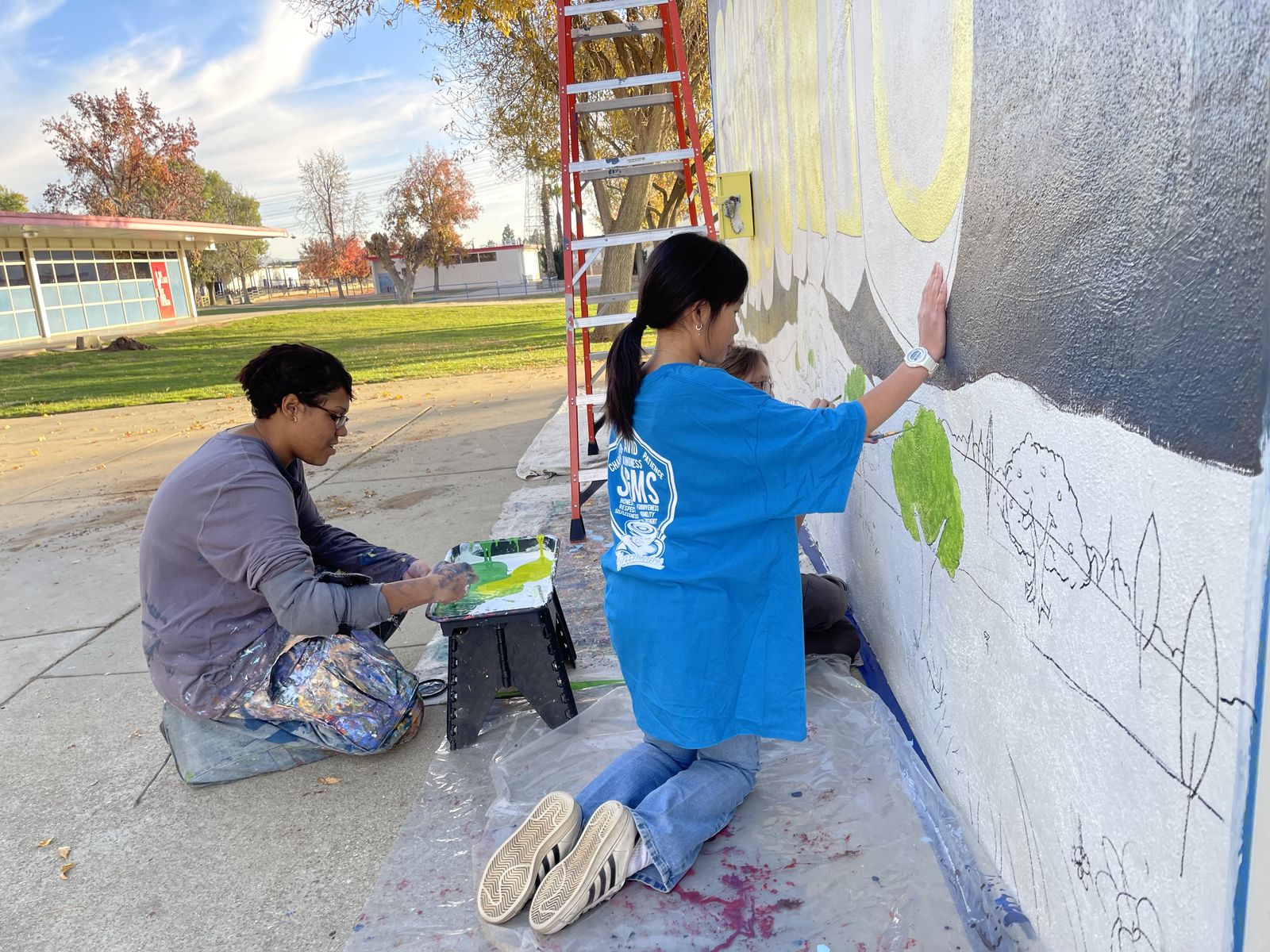 Two people painting a mural together